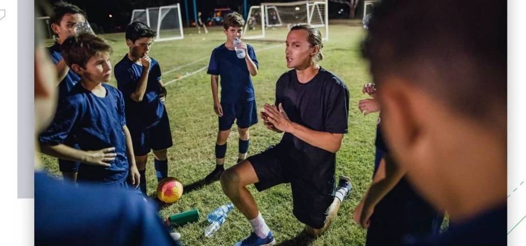 Entraineur de sport agenouillé devant son équipe de jeuens garçons