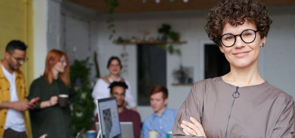 Femme au premier plan avec une équipe au travail en arrière plan
