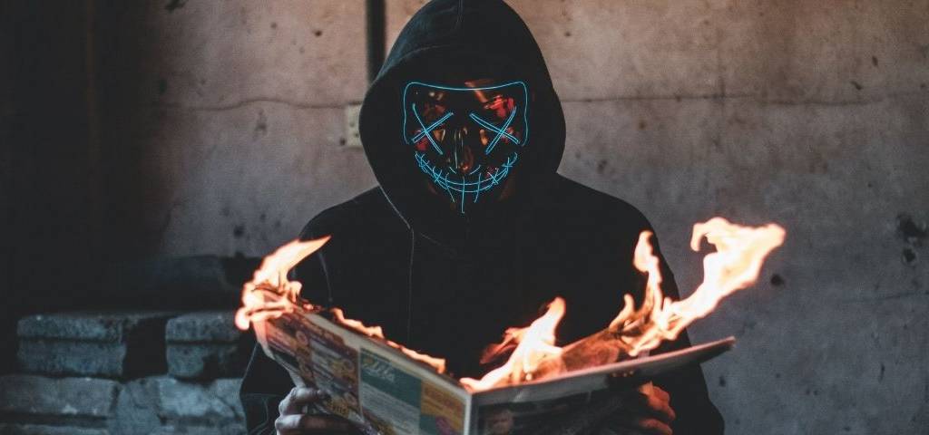 Homme masqué lisant un journal qui prend feu