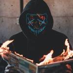Homme masqué lisant un journal qui prend feu