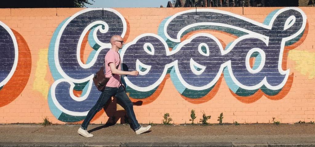 Un homme qui marche dans la rue avec un  - tag -  écrit  - good - 