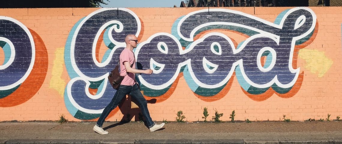 unify-partenaire-label-solidaire-whatrocks-foundation-publicite-solidaire-communication-engagement-nouvelle-consommation-sens Un homme qui marche dans la rue avec un - tag - écrit - good -