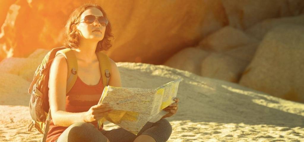 Une femme assise avec une carte et un sac à dos