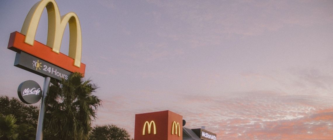 McDonald's se lance dans la production de jouets Happy Meal 100% recyclables Pancarte McDonald's sur fond de ciel rosé