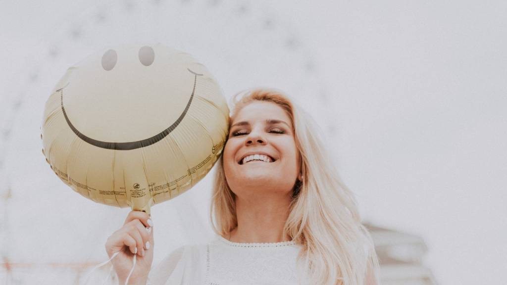 Femme sourian avec un ballon en forme de smiley