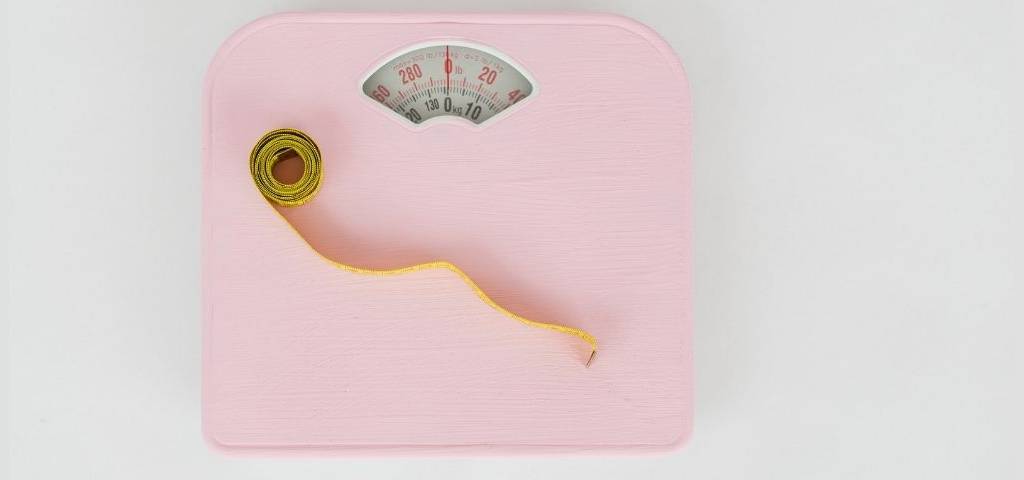 Balance rose, avec un mètre jaune posé dessus