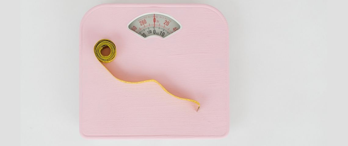 Dès septembre 2021, Camaïeu va proposer à ses clientes la possibilité d’échanger un jean en cas de prise ou de perte de poids. Balance rose, avec un mètre jaune posé dessus