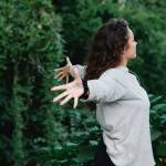 Jeune femme écratrant les bras entourée d'arbre