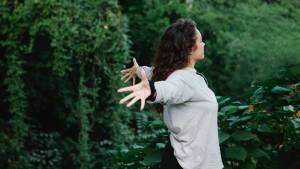 Jeune femme écratrant les bras entourée d'arbre
