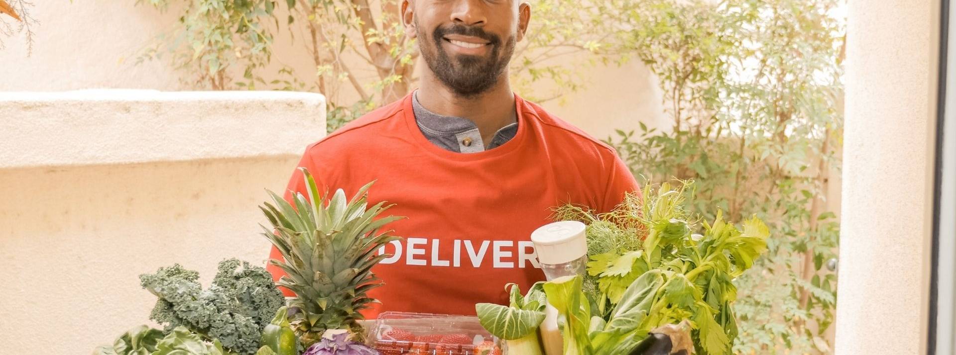 Les acteurs de livraison rapide s’engagent avec too good to go pour lutter contre le gaspillage alimentaire Homme livrant un panier de légumes