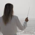 Femme en position de chef d'orchestre devant l'océan