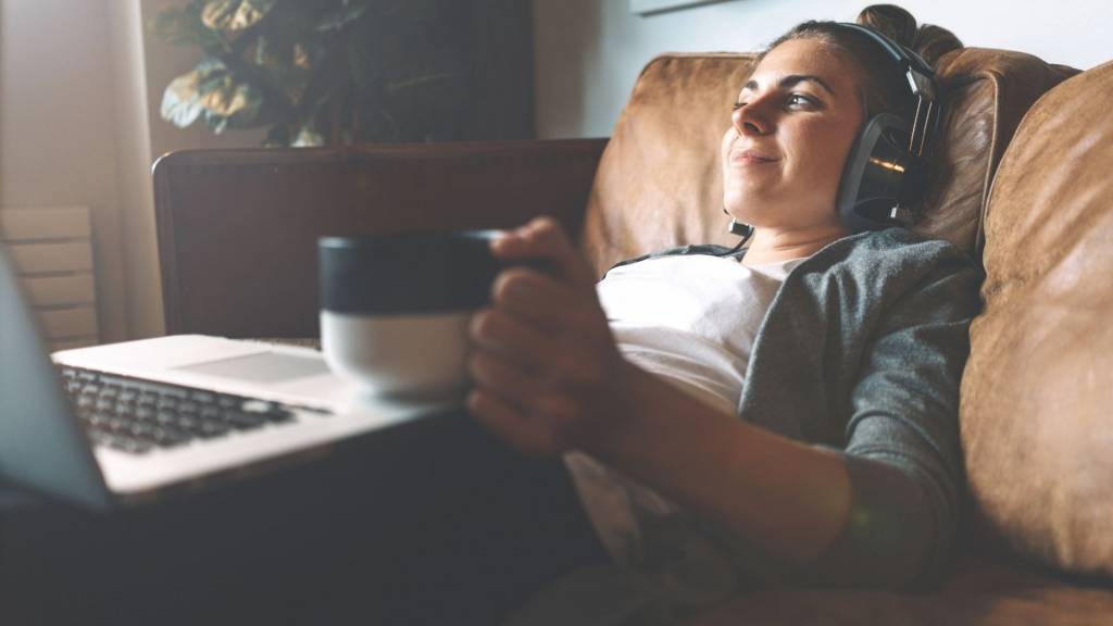 Femme allongée dan un canapé avec un casque sur les oreilles