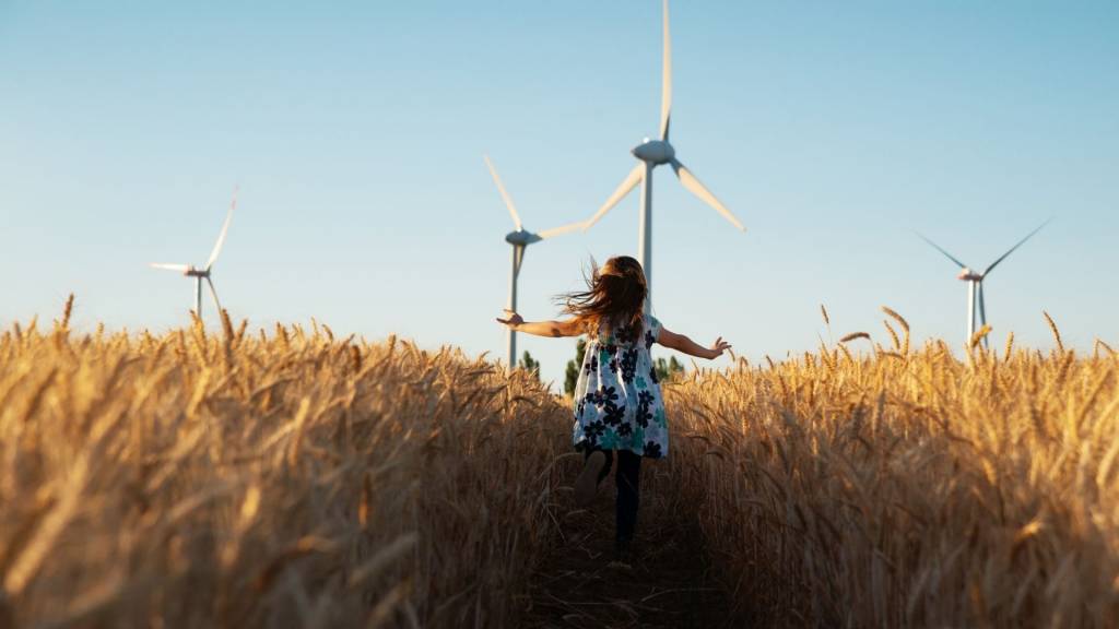 Petite fille dans un champ de blé avec des éoliennes