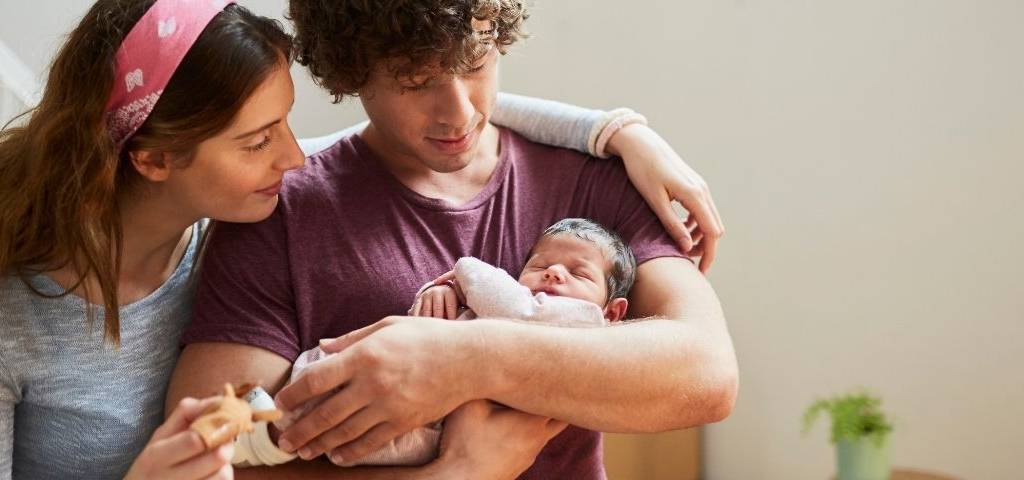 De jeunes parents avec leur bébé dans les bras.