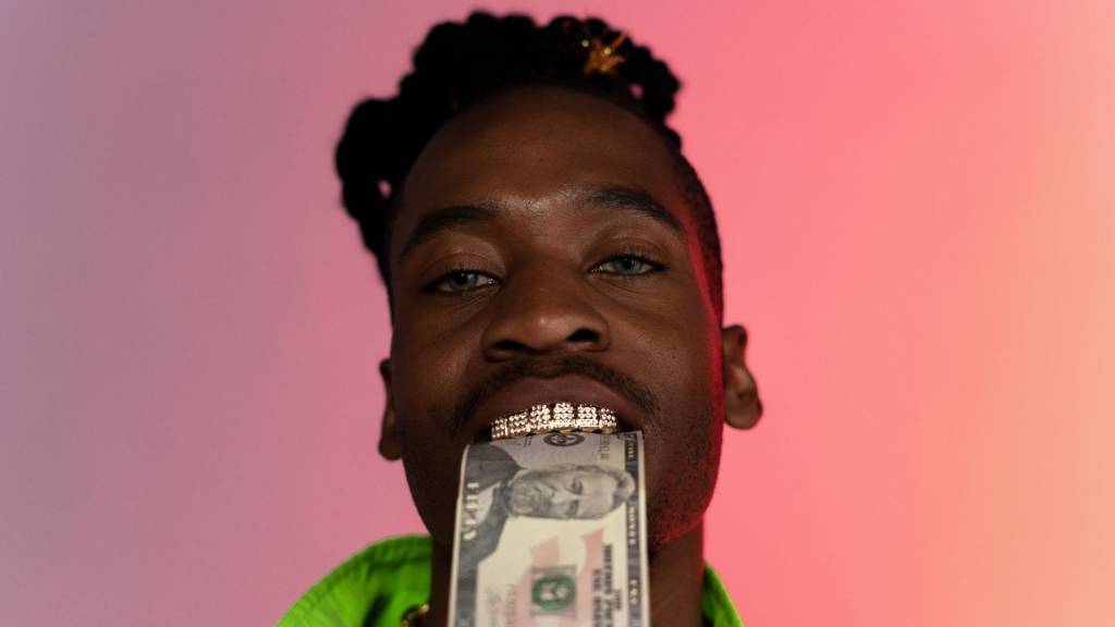 Rappeur avec des dents en argen et un billet dans entre ses dents