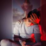 Jeune femme se tenant la t^te devant son smartphone