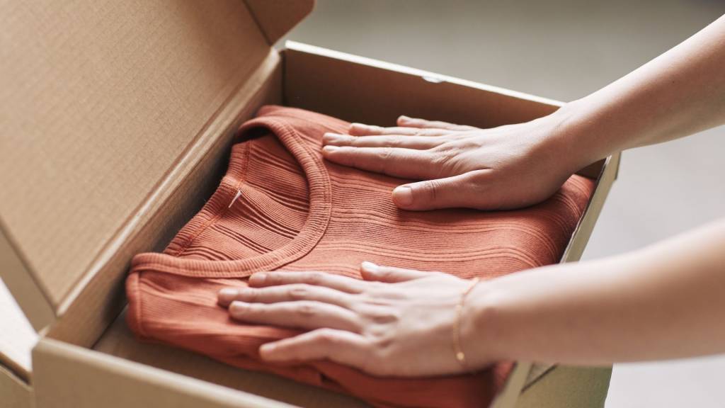 femme qui met un pull dans une boite en carton