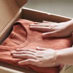 femme qui met un pull dans une boite en carton