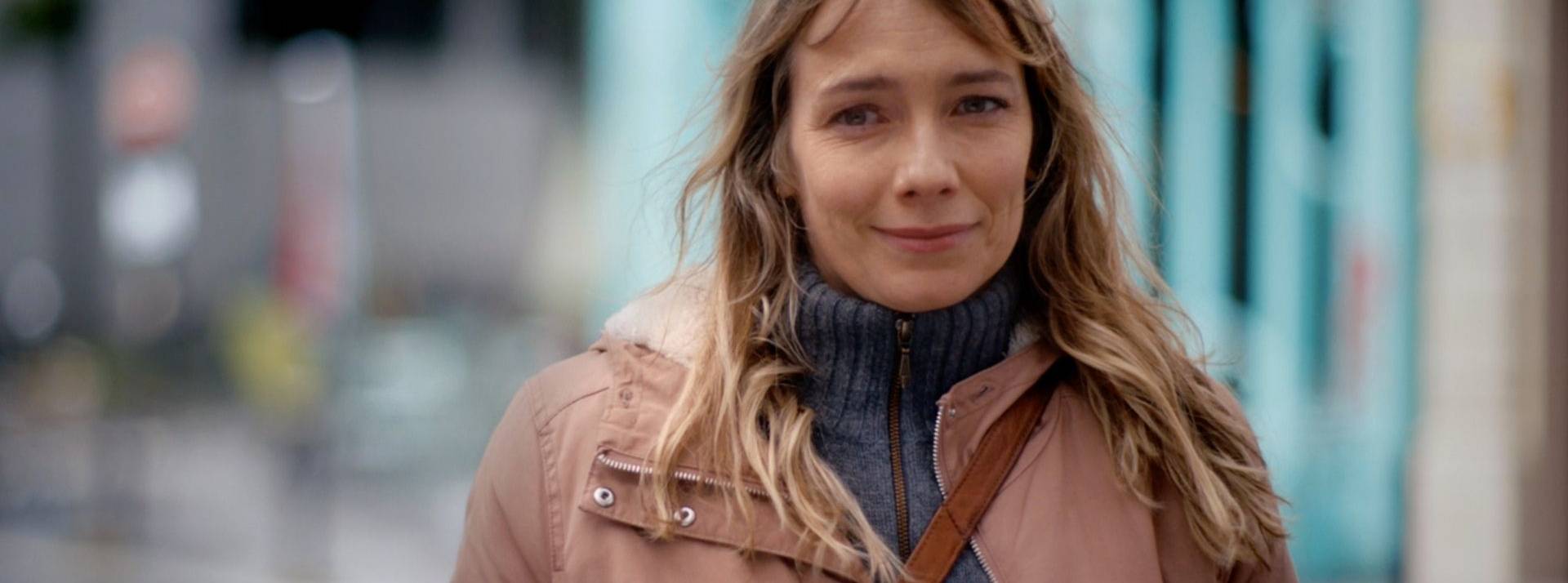 La campagne Fondation Abbé Pierre est signée FRED & FARID Paris Femme souriante se promenant dan la rue
