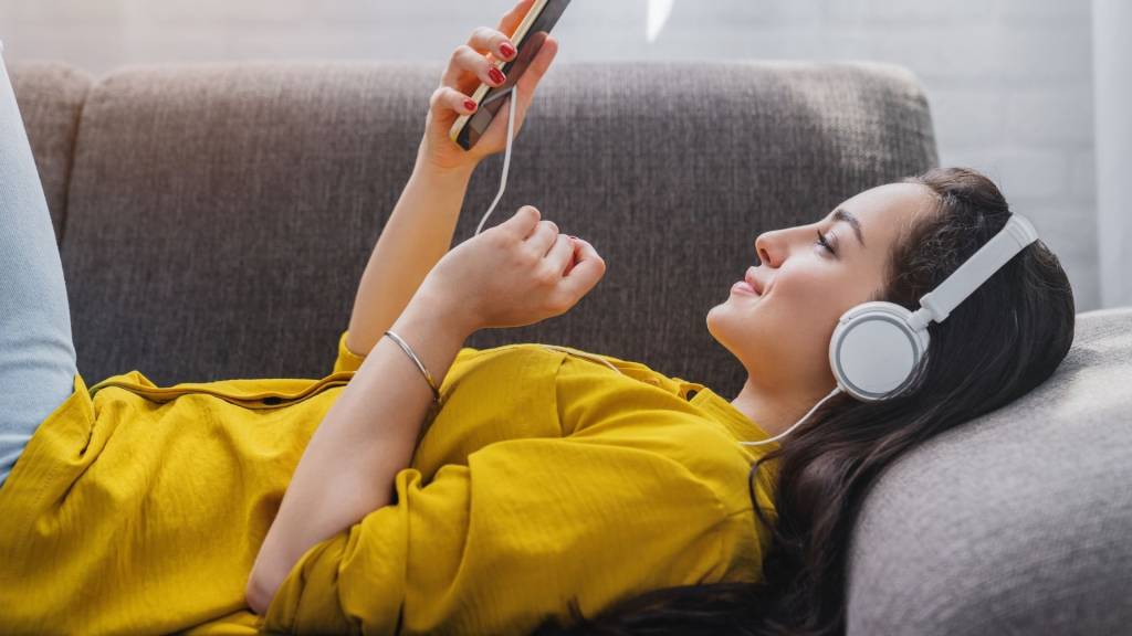 jeune femme écoutant la musique en ligne sur le smartphone dans le casque