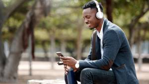 homme assis sur un banc avec un casque sur les oreilles et un smartphone dans la main