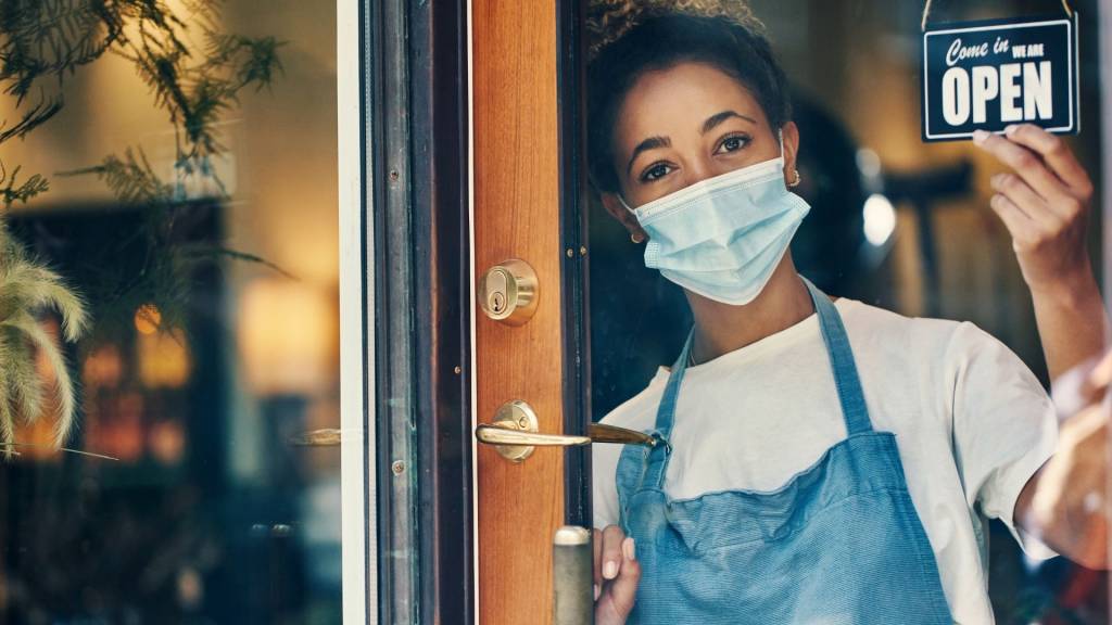 Femme à la porte de sa boutique avec un écriteau  - open - 