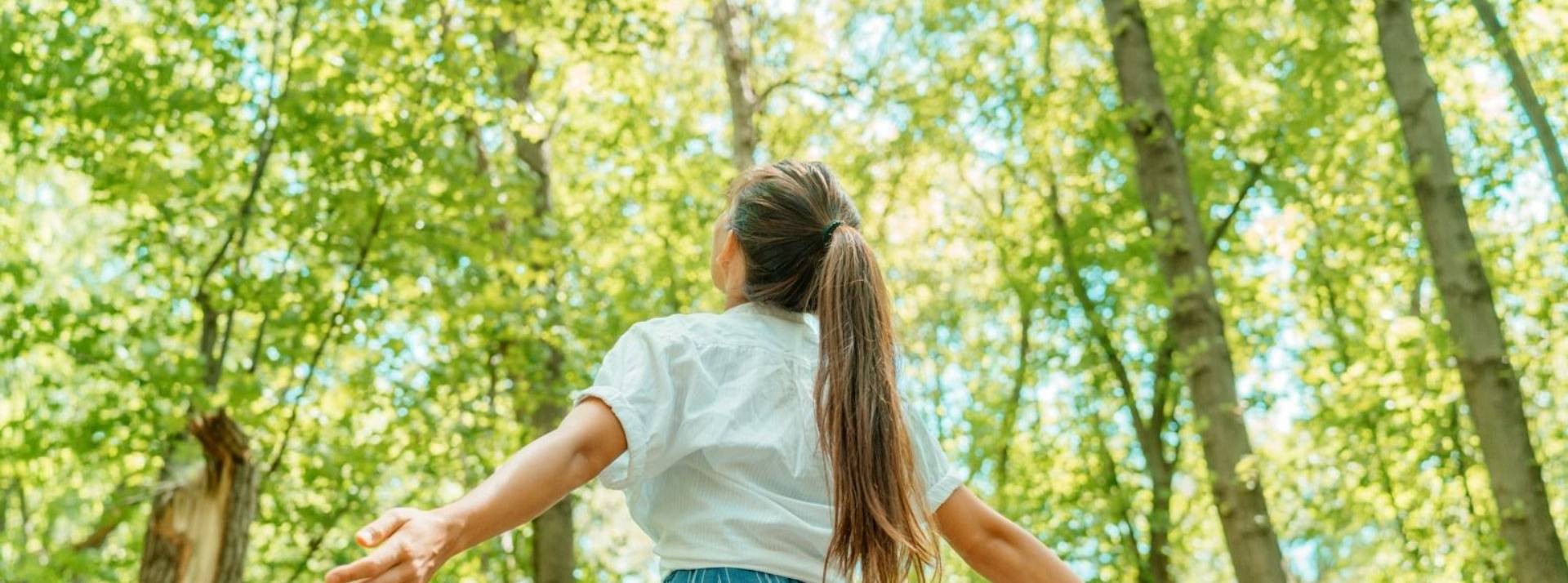 Ma French Bank, la banque 100% mobile de La Banque Postale, lancée il y a deux ans, dévoile une offre engagée avec Le Compte Idéal. Jeune fille levant les bras devant une forêt