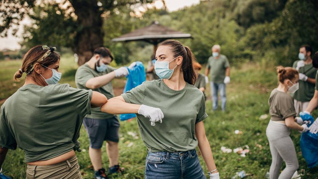 Groupe de volontaires avec des masques chirurgicaux nettoyant la nature ensemble