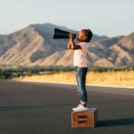 Jeune fille sur une caisse en bois avec un mégaphone
