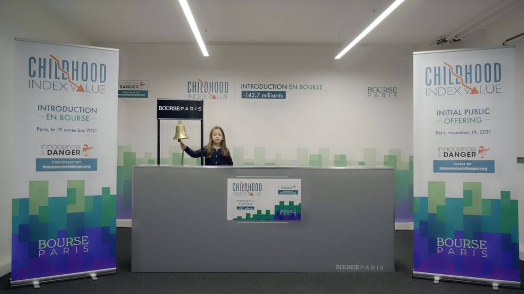 Innocence en Danger et l’agence Babel font rentrer l’enfance en Bourse pour attirer l’attention du monde de la finance. Enfant derrière un comptoir sonnant une cloche type bourse
