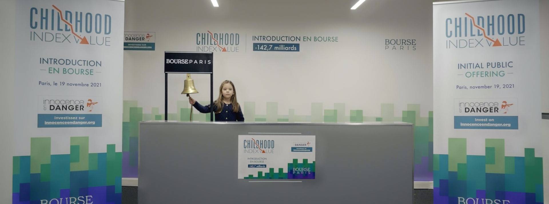 Innocence en Danger et l’agence Babel font rentrer l’enfance en Bourse pour attirer l’attention du monde de la finance. Enfant derrière un comptoir sonnant une cloche type bourse