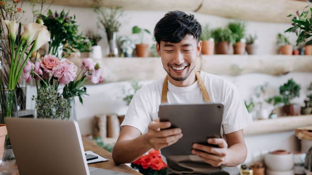 Fleuriste dans sa boutique tenant une tablette