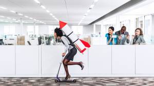 Femme sur une trotinette avec une fusée dans le dos, roualt dans des bureaux de travail