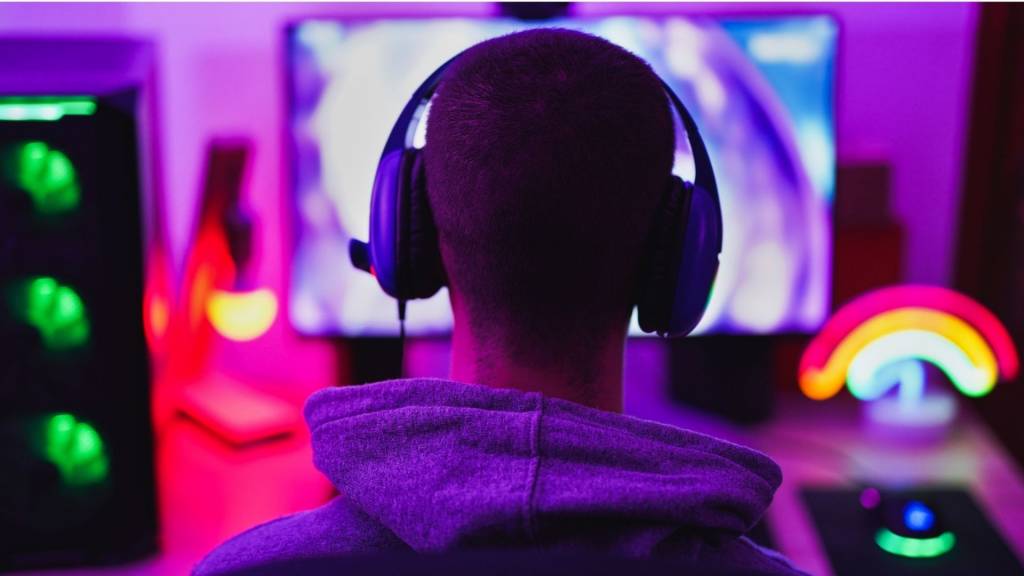 Jeune homme utilisant le casque et jouent aux jeux vidéo d’ordinateur en ligne