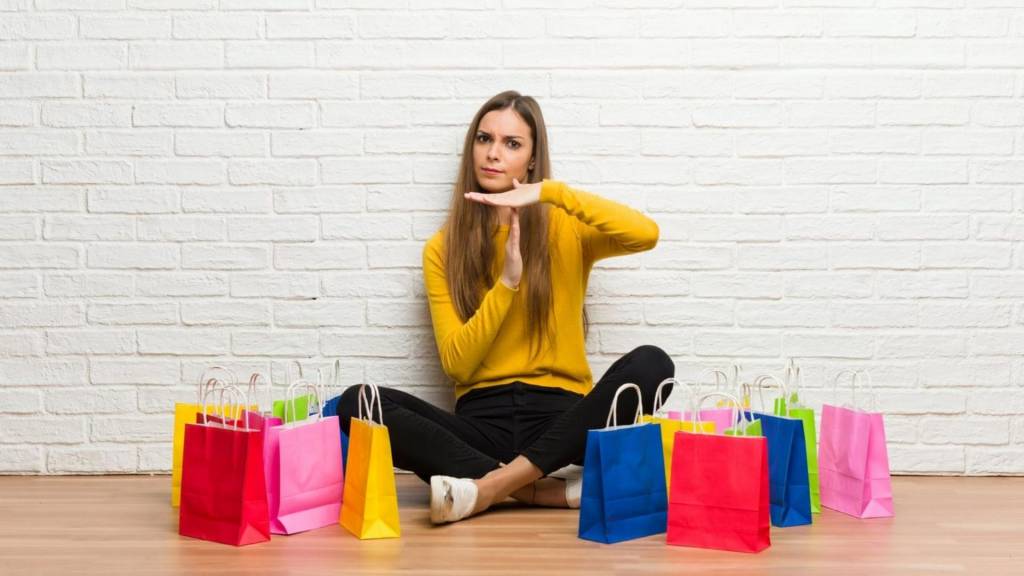 Femme faisant stop avec sa main, entouré de sacs de shopping