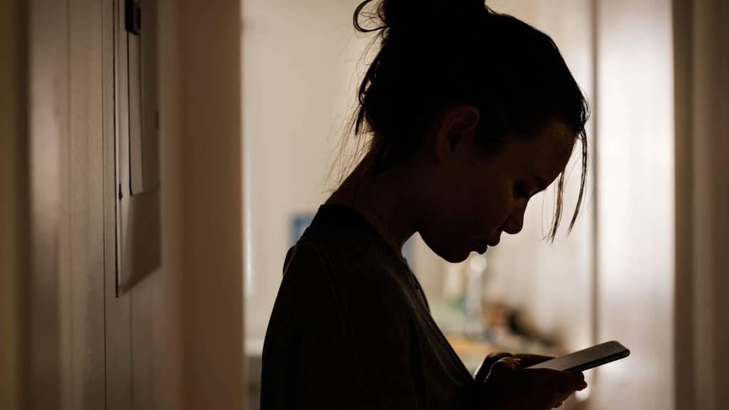 Jeune fille devant son smartphone dans le noir