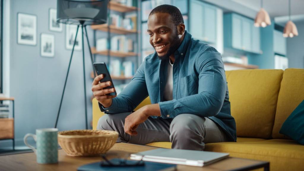Homme assis sur un canapé avec un smartphone dans les mains