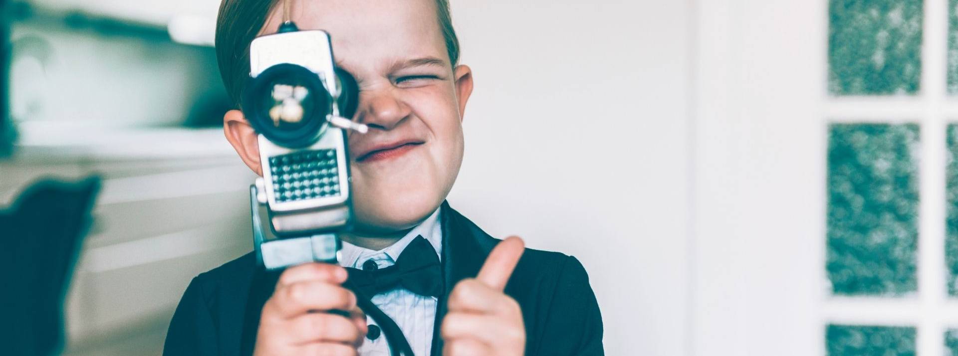 ShowHeroes Group, fournisseur indépendant européen de solutions vidéo numériques pour les éditeurs et les annonceurs, annonce le rachat de PlayAd Media Group Les pouces en l'air de garçon avec une caméra rétro tournage vidéo