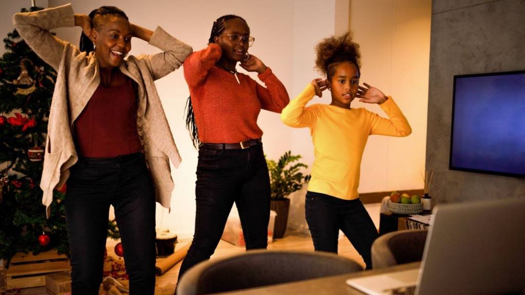 Une mère et ses filles reproduisant une chorégraphique qu'elles visonnenent sur un ordinateur portable