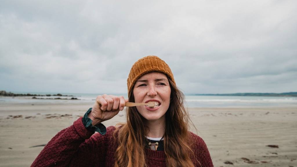 Femme se brossant les dents avec une plage en arrière plan
