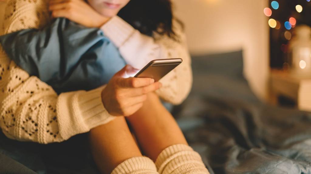 Fille dans le lit avec un téléphone