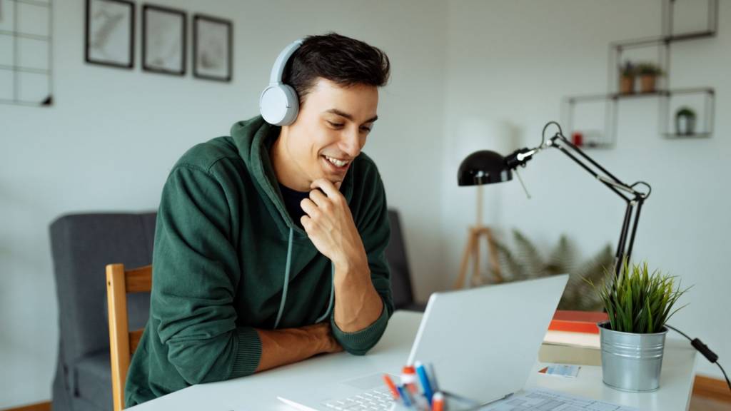 Homme avec un casque sur les oreilles devant un ordinateur portable