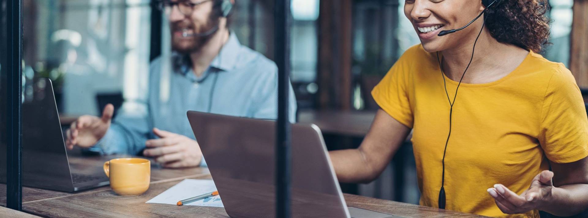 Boulanger, premier retailer français à obtenir la certification « Relation Client France » de l’AFRC et de l’Association Pro France 2 personnes el igne avec un casque audio devant un ordinateur