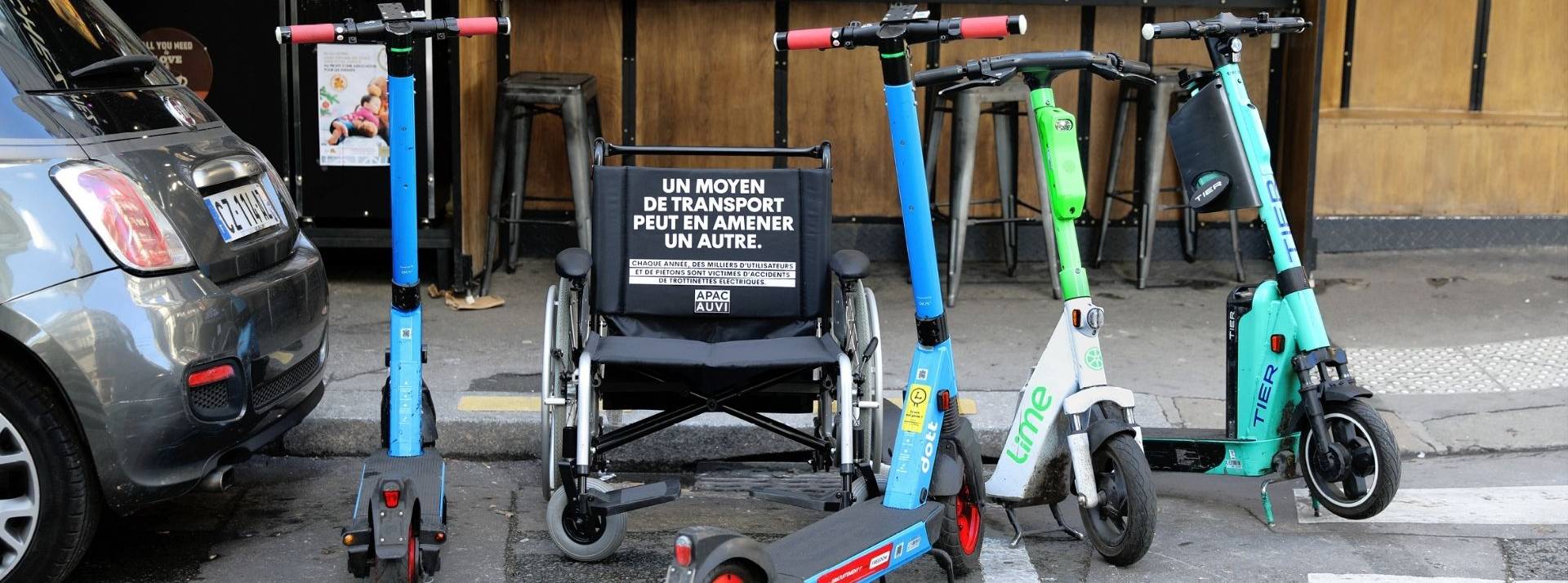 APACAUVI et MullenLowe France signent une campagne choc pour sensibiliser aux dangers des trottinettes éléctriques. Fauteuil handicapé sur une place réservé, entouré de trottinettes