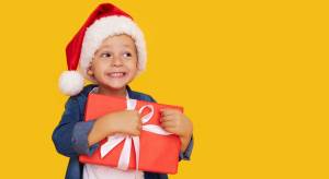 Enfant avec un chapeau de père noel tenant dans ses bras un cadeau