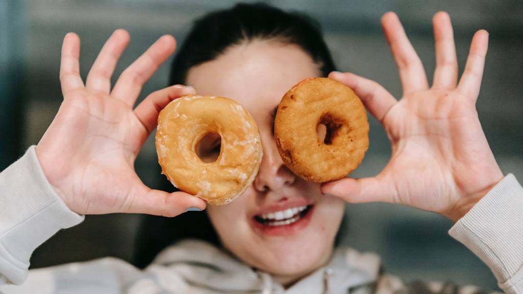 Femme se cachant chaque oeil avec un donuts