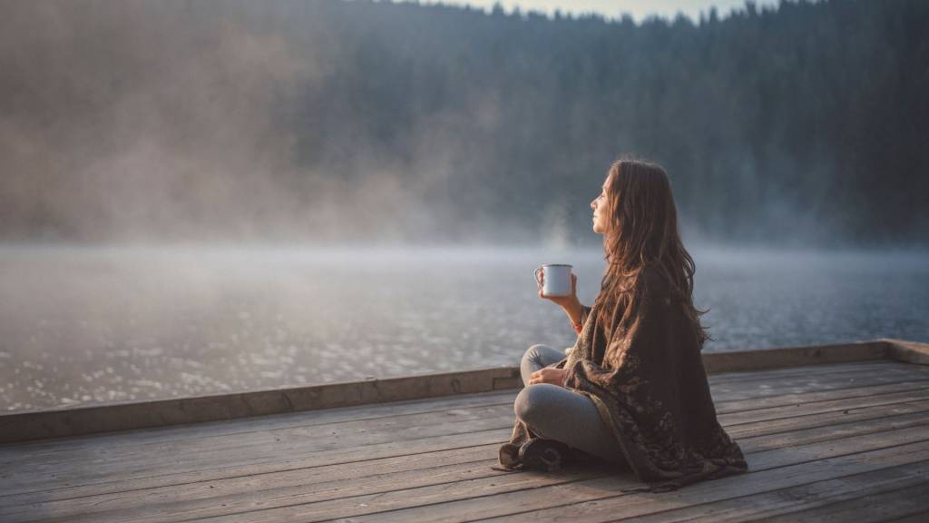 Femme buvant un café au bord d'un lac