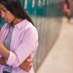 Étudiant se penchant sur le casier avec smartphone à l’école