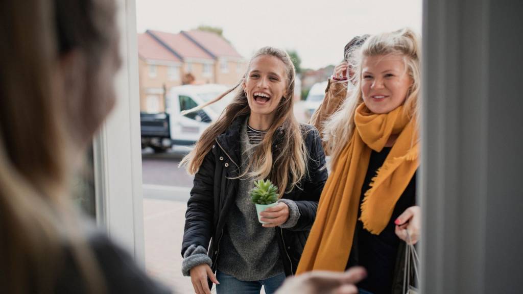 Porte s'ouvrant sur un groupe de jeunes filles souriantes