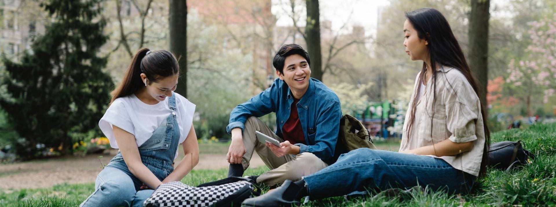 L’ESSEC & CY Cergy Paris Université lancent le BACHELOR ACT, nouvelle formation Bac+3 pour conduire les transitions écologiques, citoyennes et sociétales. 3 étudiants assis sur une pelouse